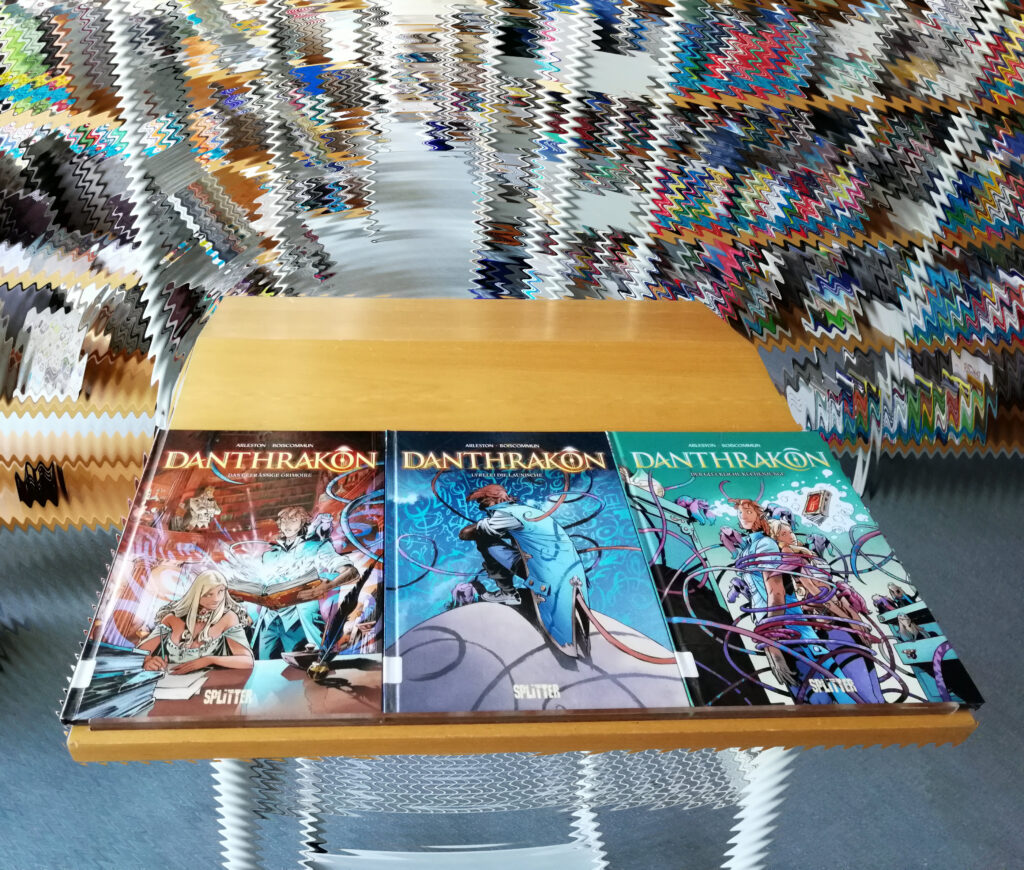Die 3 Bände der Comic-Reihe Danthrakon auf einem Podest in der Bibliothek